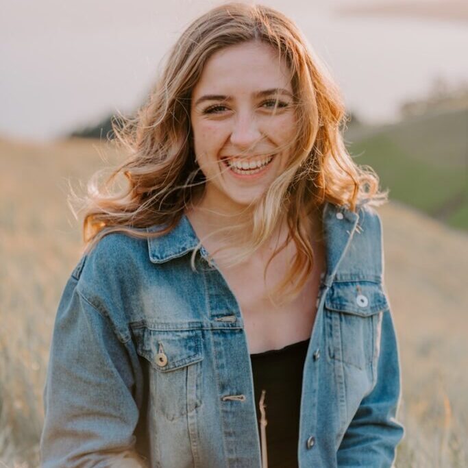 smiling woman sitting on grass during daytime